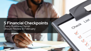 Business owner reviewing a checklist while writing in a notebook, representing financial checkpoints to review in February.