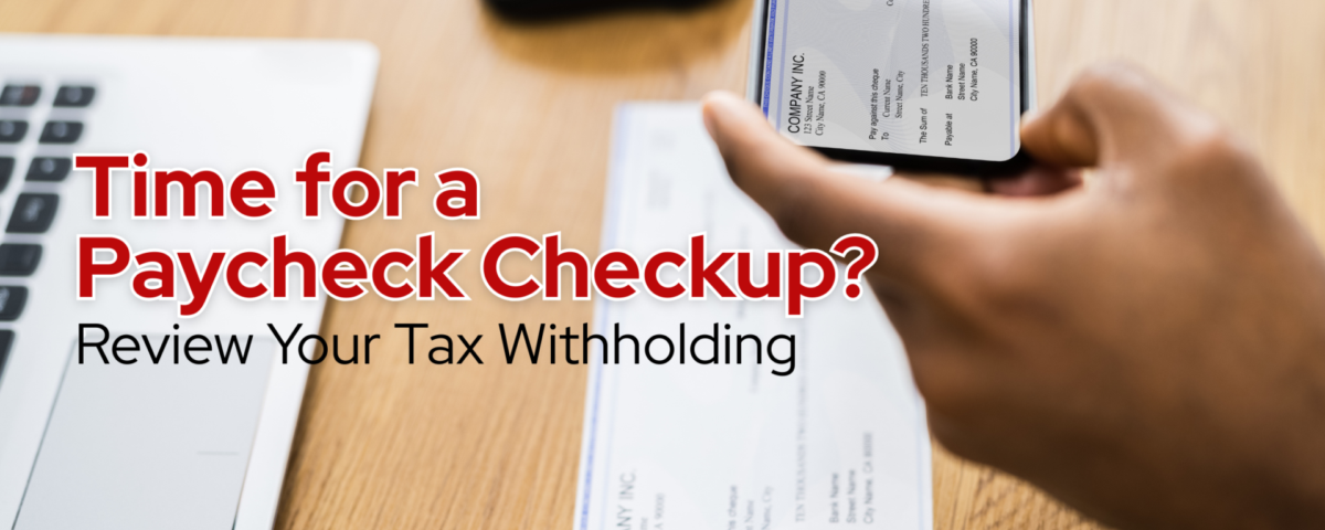 tax withholding and payrolll details being reviewed with a paycheck and mobile banking app