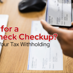 tax withholding and payrolll details being reviewed with a paycheck and mobile banking app