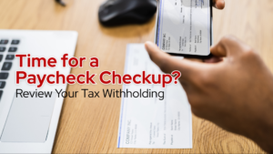tax withholding and payrolll details being reviewed with a paycheck and mobile banking app